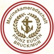 Das Bild zeigt das Emblem der Marinekameradschaft mit einem Kreuz, einem Anker und einer Lorbeergirlande mit dem Text 'PRINZ EUGEN BRUCK/MUR' in Gold auf weißem Hintergrund, eingefasst in einem roten Kreis.
