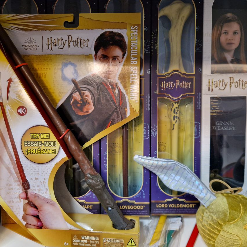 A display of Harry Potter themed merchandise, including wands, a wand box, and a golden ball, all from the Wizarding World.
