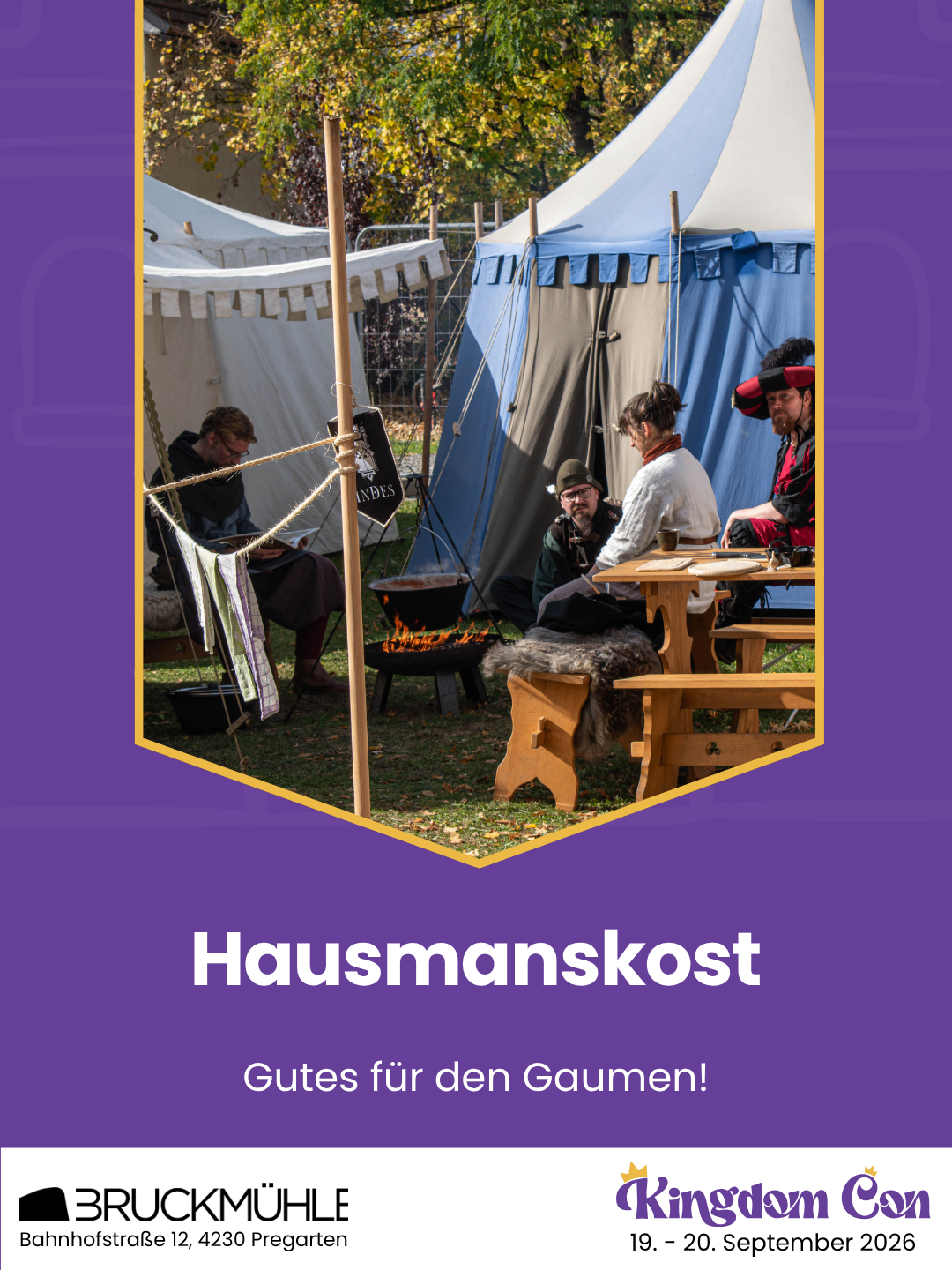 Eine Gruppe von Menschen in mittelalterlicher Kleidung sitzt um ein Feuer und einen Tisch herum, möglicherweise bei einer historischen Nachstellung.