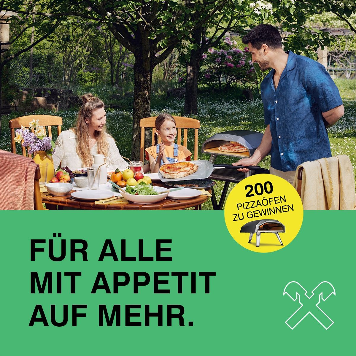 Eine Familie genießt eine Mahlzeit im Garten, während ein Mann Pizza in einem Outdoor-Ofen grillt. Ein Banner verkündet 'Für alle mit Appetit auf mehr.' Ein kreisförmiger Aufkleber bietet 200 Pizza-Chancen zum Gewinnen.