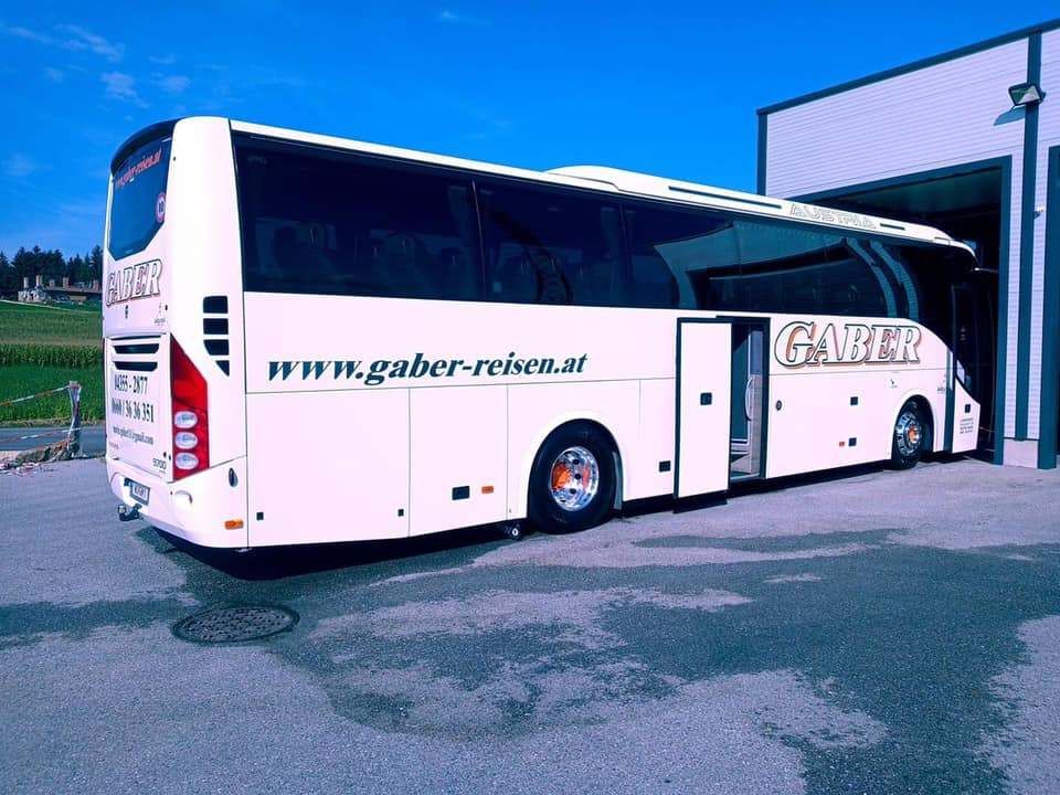Ein weißer Bus mit dem Namen GABER steht vor einem Gebäude. Die Website www.gaber-reisen.at ist auf der Seite sichtbar.