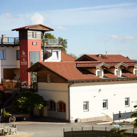 Ein Hotelgebäude mit rotem Dach und Turm. Mehrere Fenster und eine Treppe. Ein Wagen mit einem Rad davor.