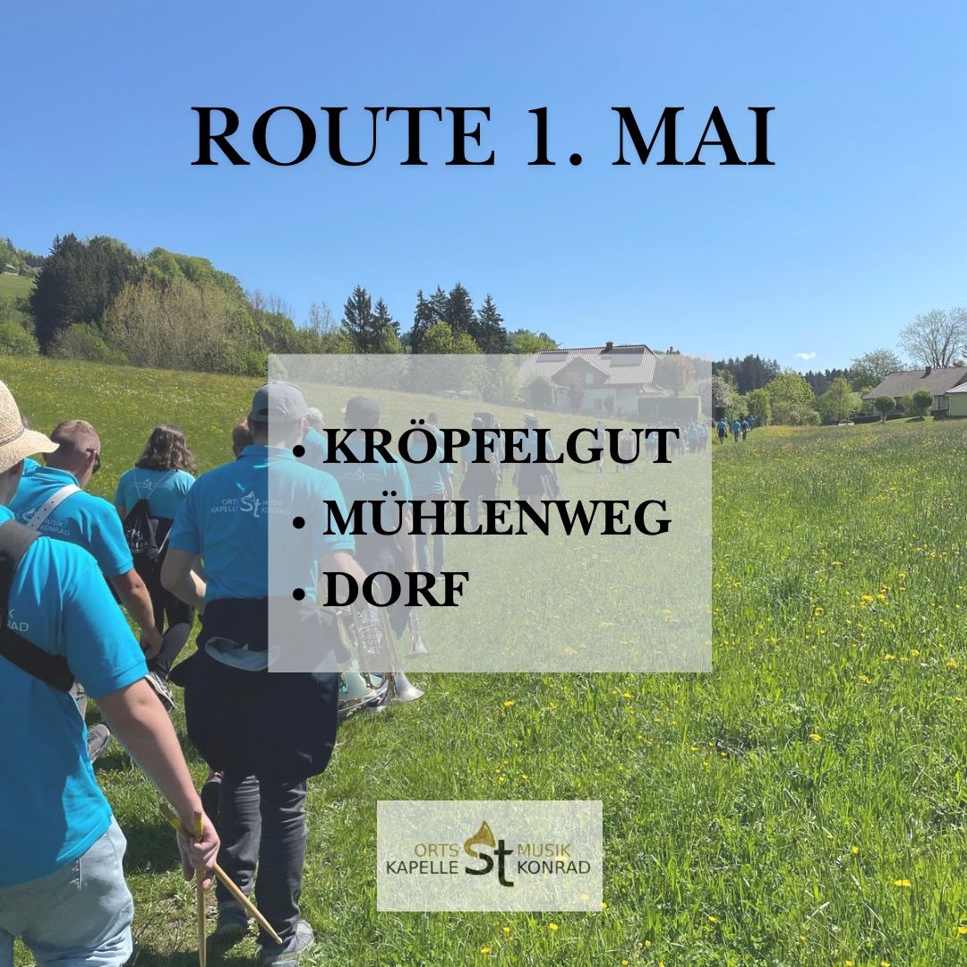 Eine Gruppe von Menschen in blauen Shirts geht auf einem Grasfeld mit einer Routenkarte. Der Text auf der Karte lautet 'Route 1. Mai' und enthält Orte wie 'Kröpfelgut', 'Mühlenweg' und 'Dorf'. Im Hintergrund sind Bäume und Häuser zu sehen.
