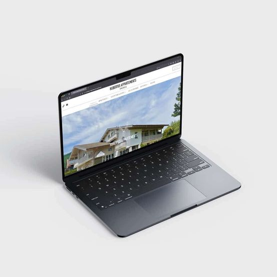 Ein Laptop mit einer Website auf dem Bildschirm. Die Website handelt von Hubertus Apartments, mit einem Hausbild und etwas Text.