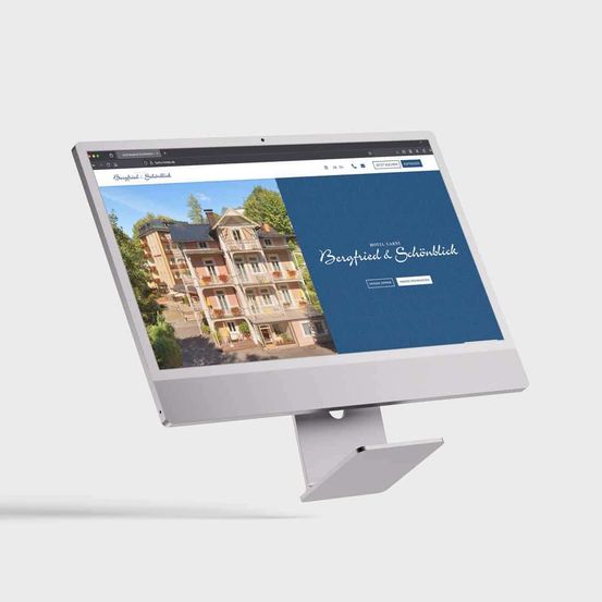 Ein Computermonitor zeigt eine Website für das Hotel Berfried & Schonblick mit einem Bild des Gebäudes.