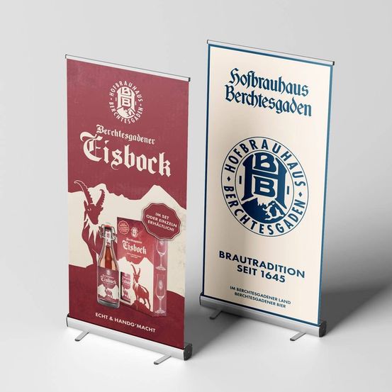 Zwei Banner mit Logo und Text sind zu sehen. Der linke Banner zeigt einen Ziegenbock und eine Bierflasche, mit dem Text 'Tisbock' und einem Logo für 'Berchtesgadener'. Der rechte Banner präsentiert ein blaues Logo und den Text 'Brautraditon seit 1645', was die Brautradition seit 1645 repräsentiert.