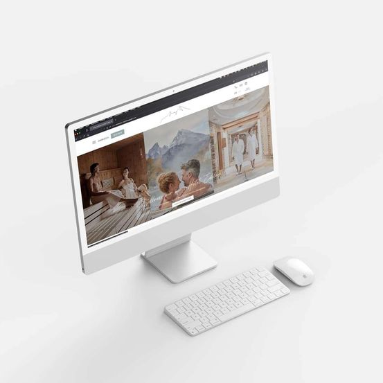 A computer monitor displays a website with images of people in a sauna. A keyboard and mouse are positioned next to the monitor.