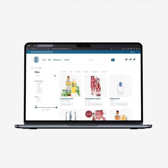 A laptop displaying a website for a shop with categories such as 'Angelteufel,' 'Bar,' 'Gläser,' 'Einkaufswagen,' and 'Souvenirs.' Product images include beverages with price tags.'
