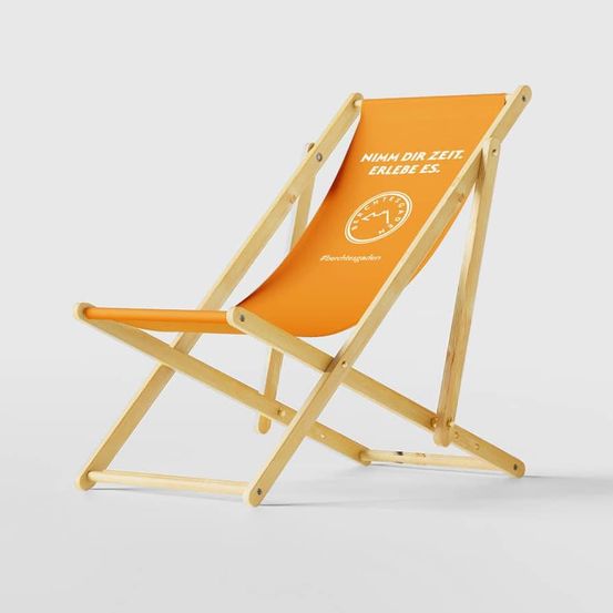An orange folding chair with a white and orange backrest on a white background. The backrest has text and a logo.