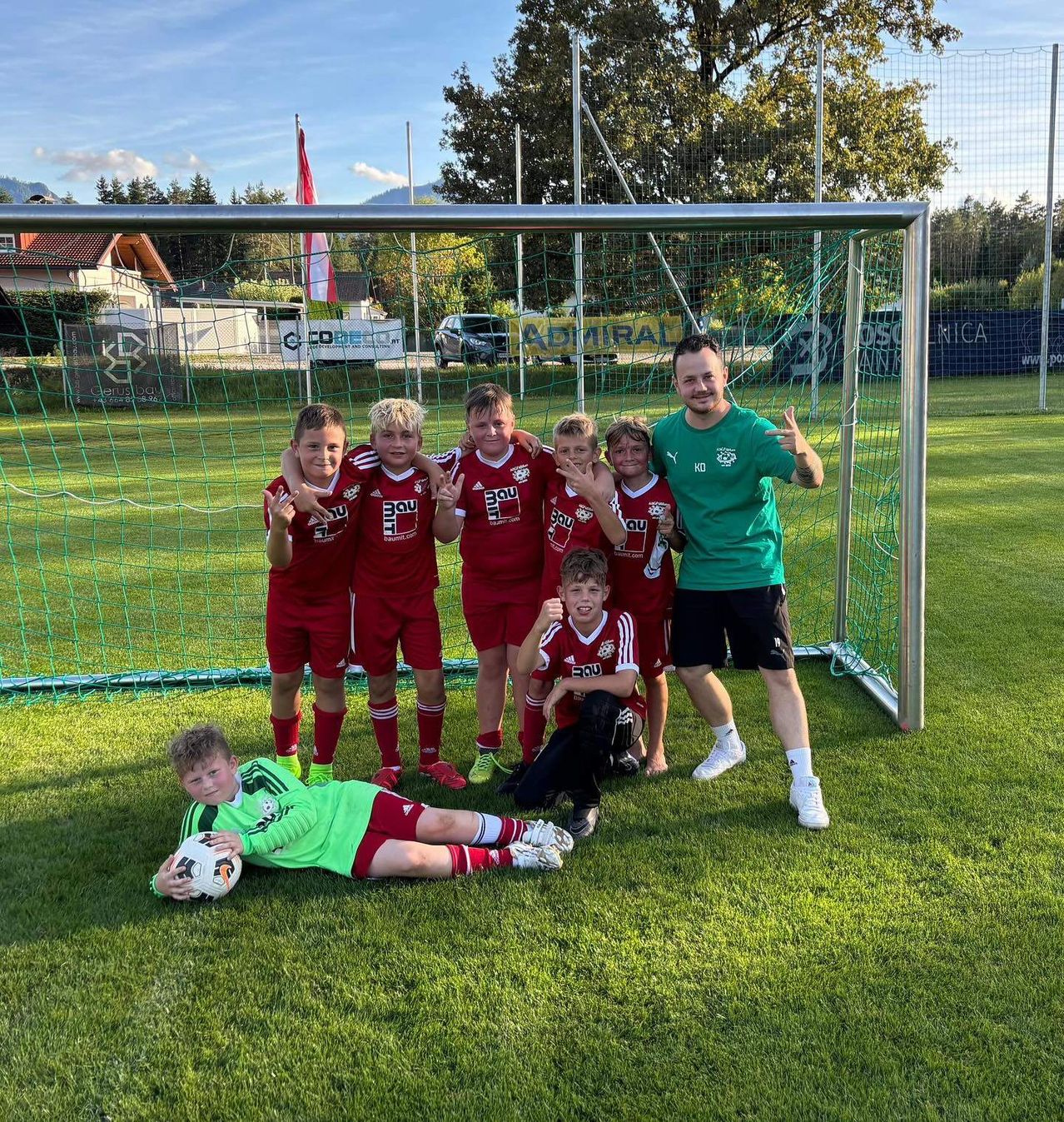 Eine Gruppe junger Fußballer in roten Trikots posiert für ein Foto vor einem Tor.