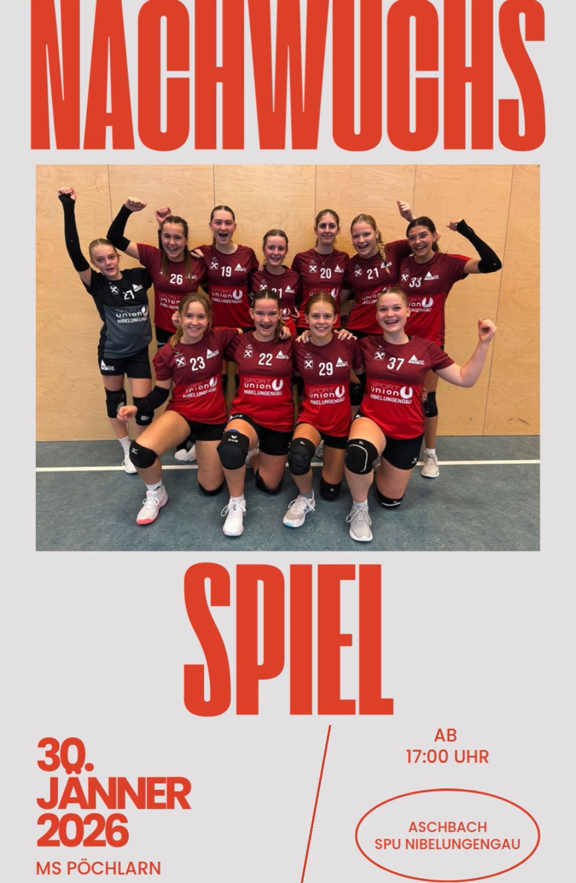 Eine Gruppe junger Frauen in Sportuniformen mit Nummern von 19 bis 37 auf ihren Trikots posiert für ein Foto. Sie sind in einem Fitnessstudio mit einer Holzwand und einem blauen Boden. Das Wort 'SPIEL' ist in Rot am unteren Rand geschrieben.