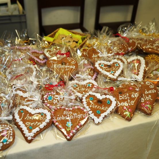 Ein Tisch voller herzförmiger Lebkuchen, einzeln in Plastik verpackt, mit Botschaften wie 'Danke' und 'Ich liebe dich' darauf geschrieben.