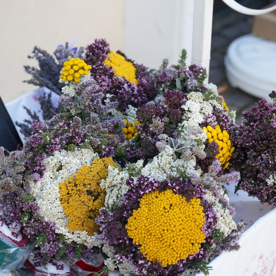 Ein Nahaufnahme eines farbenfrohen Straußes aus getrockneten Blumen, bestehend aus einer Mischung aus gelben, weißen und lila Blüten, in einer dekorativen Anordnung.
