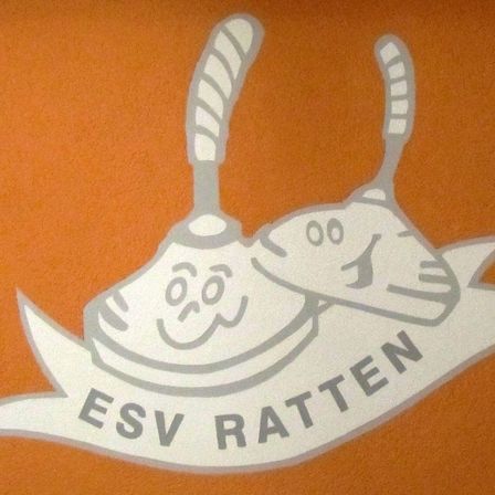 Ein orangefarbener Hintergrund zeigt ein Logo mit zwei Glocken, jeweils mit einem lächelnden Gesicht, und dem Text ESV RATTEN darunter.