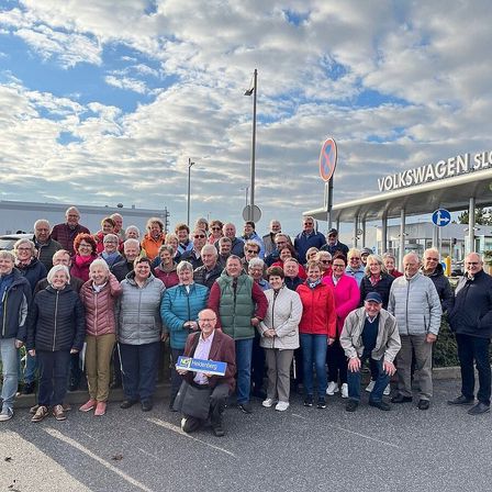 Eine Gruppe von Menschen posiert für ein Foto vor der Volkswagen Slowen Fabrik. Sie tragen Winterkleidung. Einige von ihnen halten Plakate.