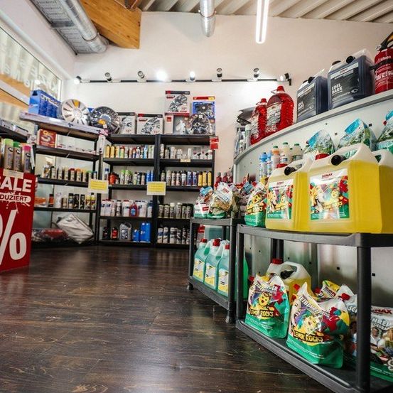 Ein Laden mit Holzboden hat Regale voller Autopflegeprodukten und Reinigungsmitteln. Die Produkte umfassen Flaschen, Dosen und Tüten. Die Regale sind ordentlich organisiert.