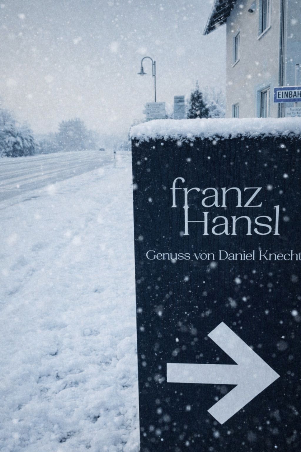 Eine verschneite Straße mit einem großen Schild davor. Das Schild trägt den Text 'franz Hansl Genuss von Daniel Knecht'. Schnee bedeckt den Boden und die Bäume im Hintergrund.