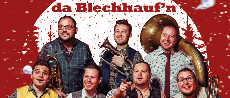 Ein festliches Gruppenfoto von Musikern vor rotem Hintergrund. Sie halten Blechblasinstrumente und lächeln in die Kamera. Der Text lautet 'Wir sagen Euch an!'.