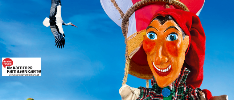 Ein Plakat für Kasperls Weltreise mit einer Marionette im Korb. Eine Werbung für eine Sonntagsveranstaltung am 18. Januar um 16:00 Uhr im Haus der Musik in Wolfsberg-St. Stefan.