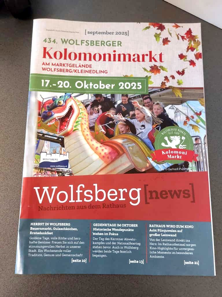 Ein Plakat für den 434. Wolfsberger Kolomonmarkt am Marktplatz Wolfsberg/Kleinedling vom 17.-20. Oktober 2025. Es zeigt einen Drachen, Menschen auf einer Achterbahn und Herbstblätter. Der Text enthält Details zu Veranstaltungen wie der Erntezeit in Wolfsberg, historischen Wendepunkten und dem Rathaus, das zu einem Kino wird.