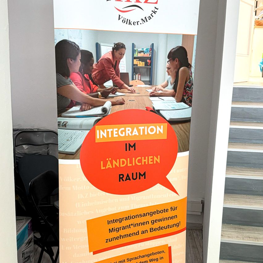 Ein Plakat mit einem Bild von Menschen, die um einen Tisch sitzen und lernen. Das Plakat besagt 'Integration im lokalen Raum'.