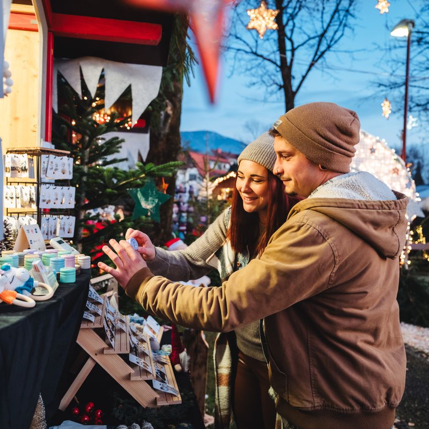 Ein Paar betrachtet Weihnachtsdekorationen in einem Markt mit festlicher Atmosphäre.