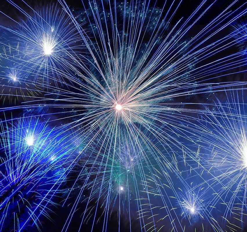 Eine farbenfrohe Feuerwerksshow mit mehreren Farben, darunter Blau, Grün und Weiß, am dunklen Nachthimmel.