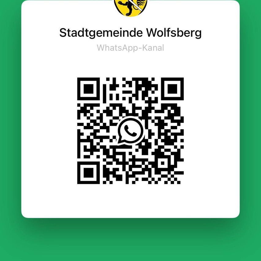Das Bild zeigt einen grünen Hintergrund mit einem weißen Rahmen. Es zeigt das Logo der Stadtgemeinde Wolfsberg und den Text 'WhatsApp-Kanal' über einem QR-Code. Der QR-Code enthält ein WhatsApp-Symbol.