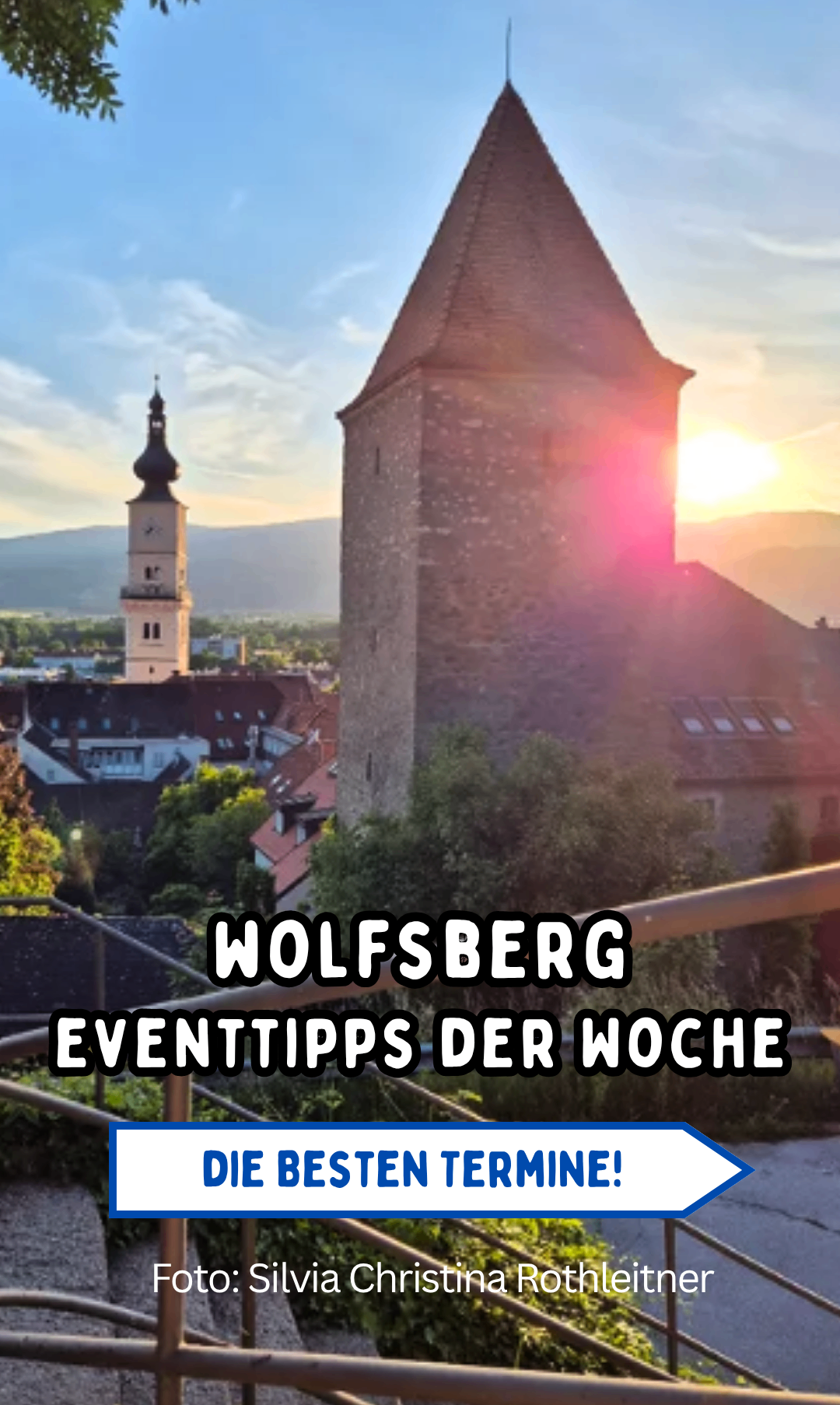A view of Wolfsberg's architecture with a setting sun in the background. The city has many buildings and trees.
