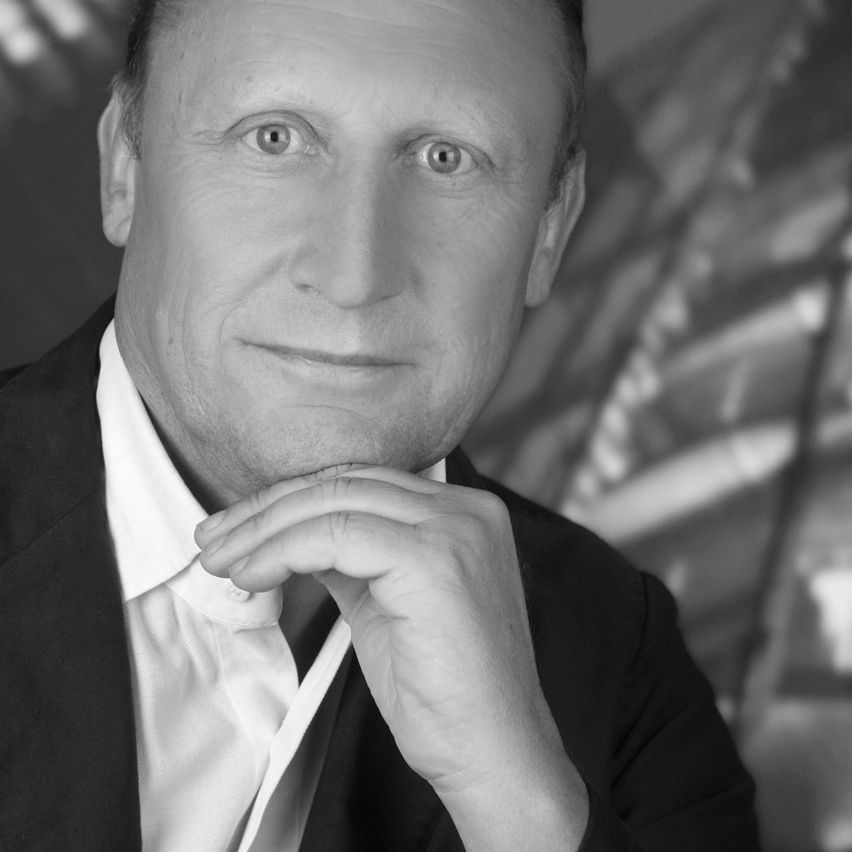 Black-and-white portrait of a man in a business suit with one hand on his chin.