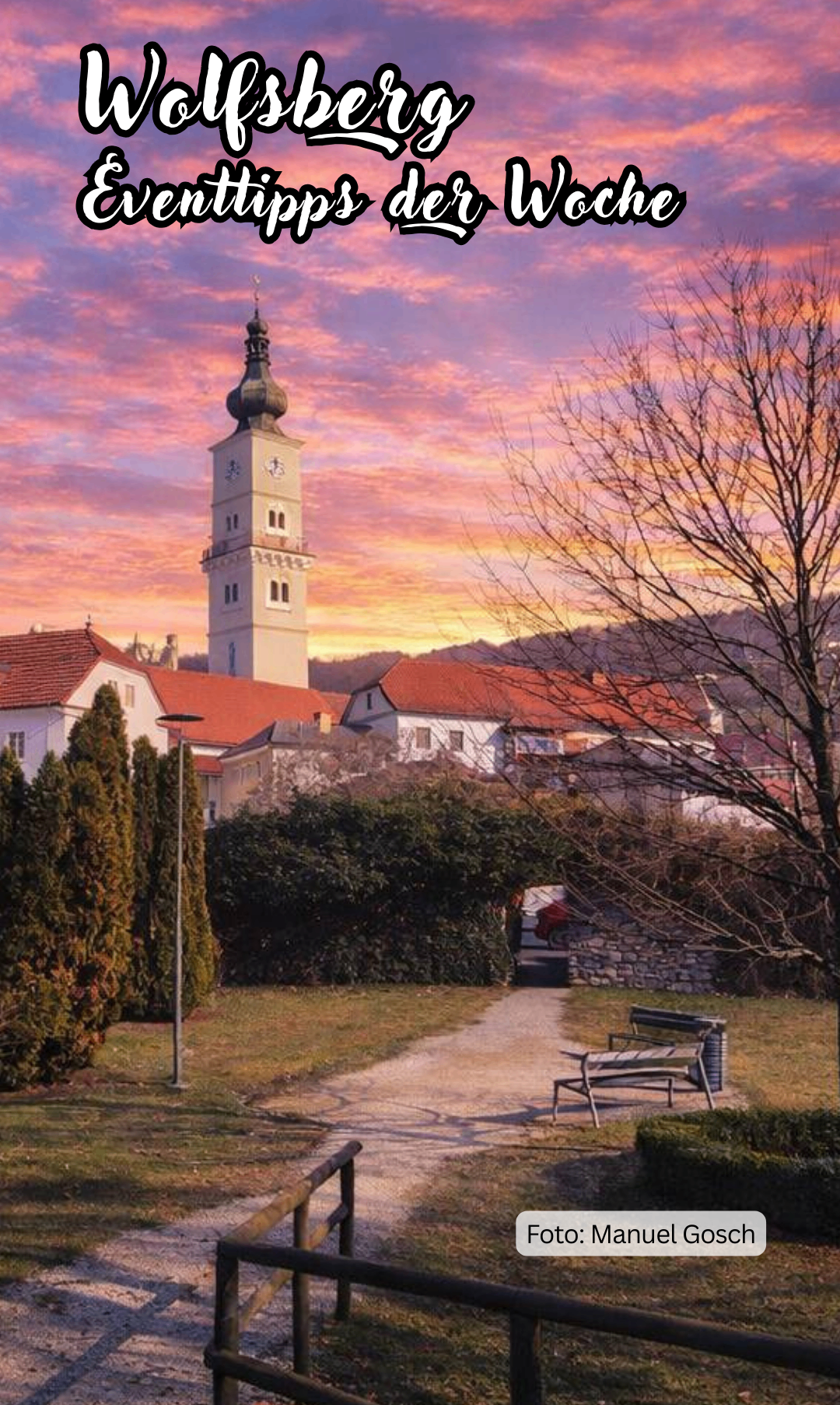 Ein hoher Turm mit einer Uhr steht vor einem Gebäude mit rotem Dach. Der Himmel ist mit Orange- und Rosatönen bemalt.