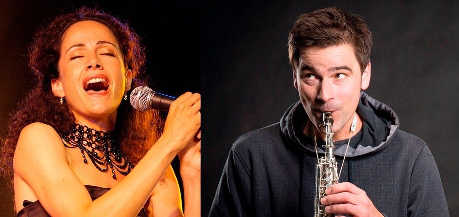 A woman sings into a microphone with her eyes closed, while a man plays a saxophone, both in a spotlight.