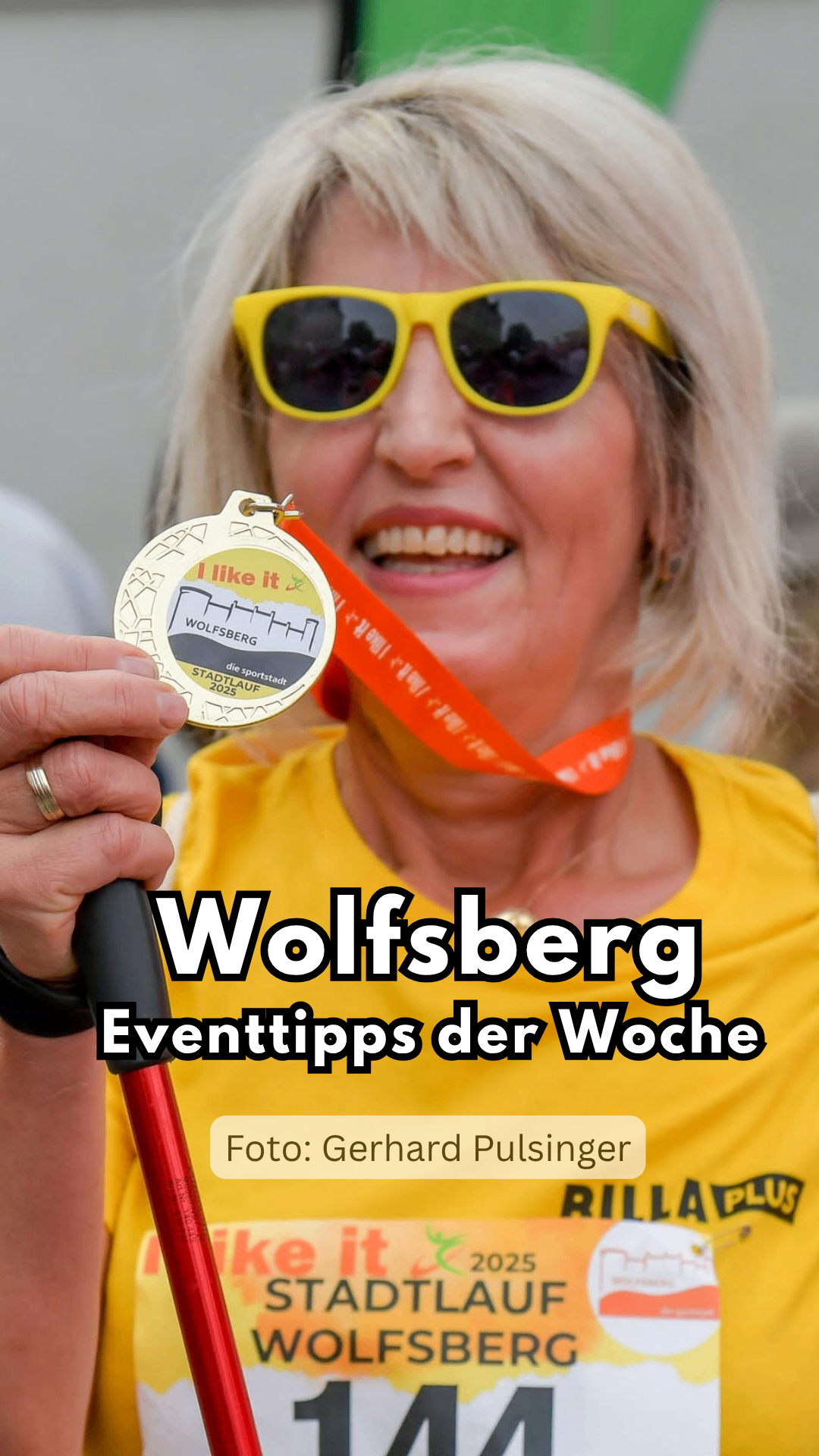 Eine Frau mit Sonnenbrille und gelbem Shirt hält eine Medaille mit dem Text 'I like it' und 'Wolfsberg'. Die Medaille ist an einem orangefarbenen Band befestigt. Das Bild hat einen Wasserzeichen mit dem Text 'Wolfsberg Eventtipps der Woche'.