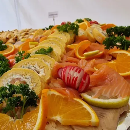 Ein Tablett mit Räucherlachs, Orangenscheiben und Petersiliengarnitur.