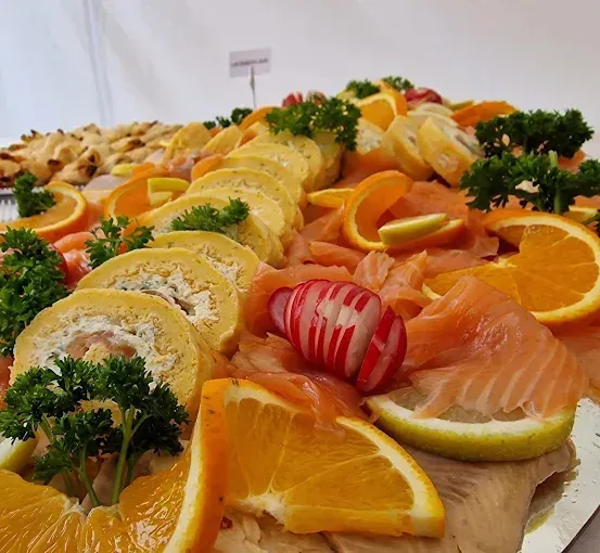 Ein Tablett mit Räucherlachs, Orangenscheiben und Petersiliengarnitur.