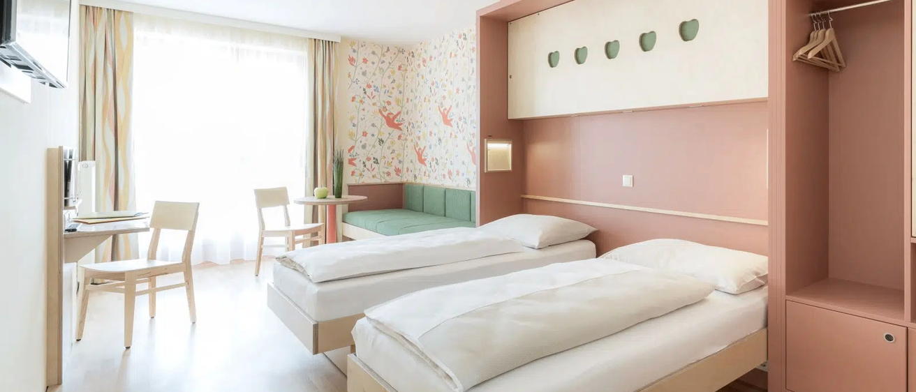 Ein Schlafzimmer mit zwei Einzelbetten und einer Couch in der Nähe eines Fensters.