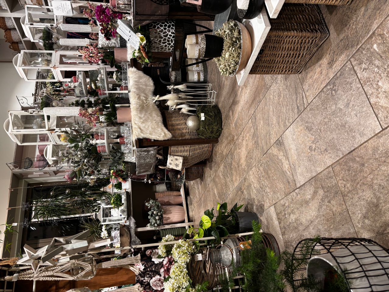 Ein Blick von oben auf einen Laden mit vielen Pflanzen, Blumen und Dekorationen. Es gibt weißes Fell und Korbkörbe auf dem Boden.