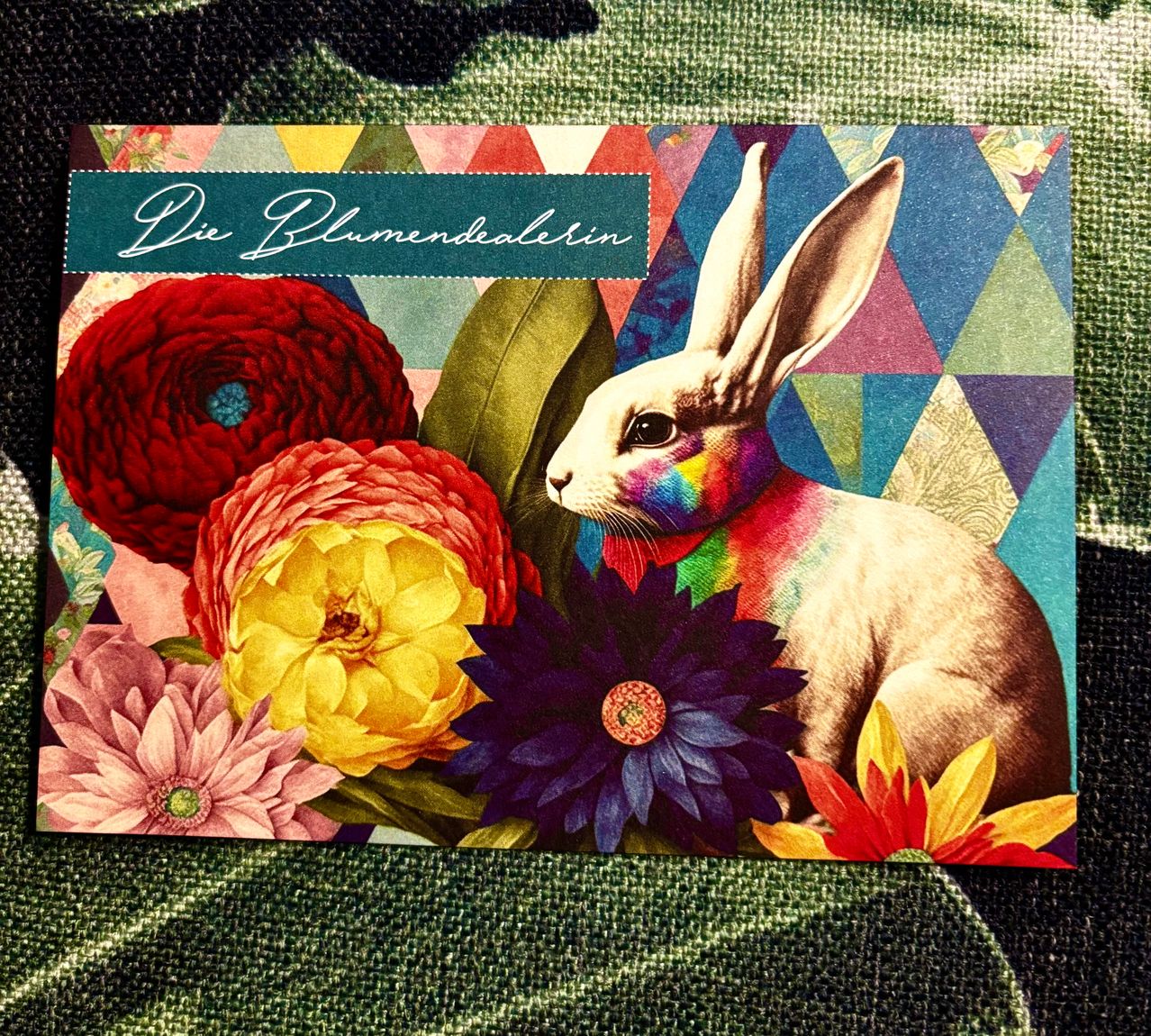 Eine Illustration eines Kaninchens mit einem Regenbogengesicht, umgeben von leuchtenden Blumen auf einem gemusterten Hintergrund.