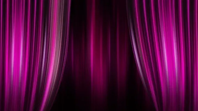 Ein Paar lila Theatervorhänge mit Licht, das von der Seite beleuchtet wird und einen dramatischen Effekt erzeugt.