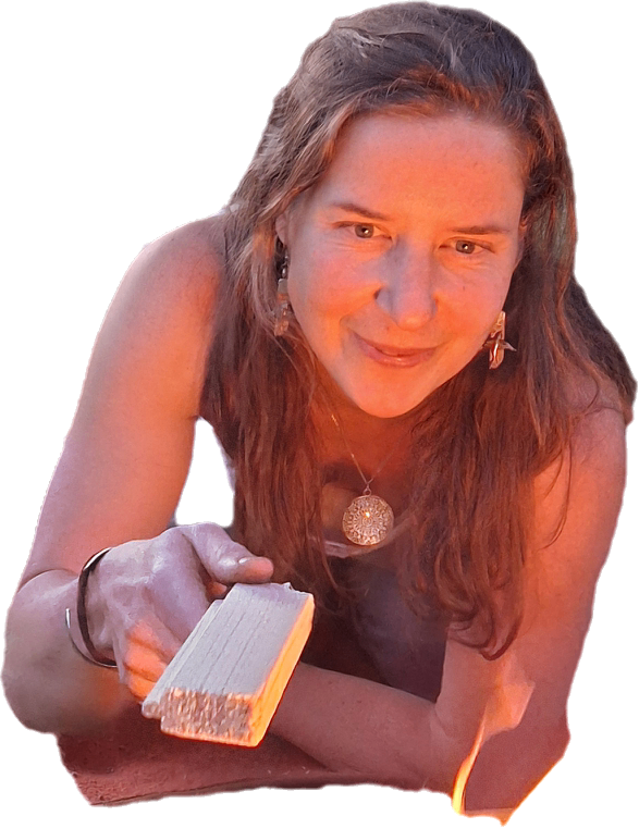 Eine Frau mit langen Haaren hält einen Holzblock, wahrscheinlich zum Holzarbeiten. Sie hat eine Halskette und Ohrringe an.