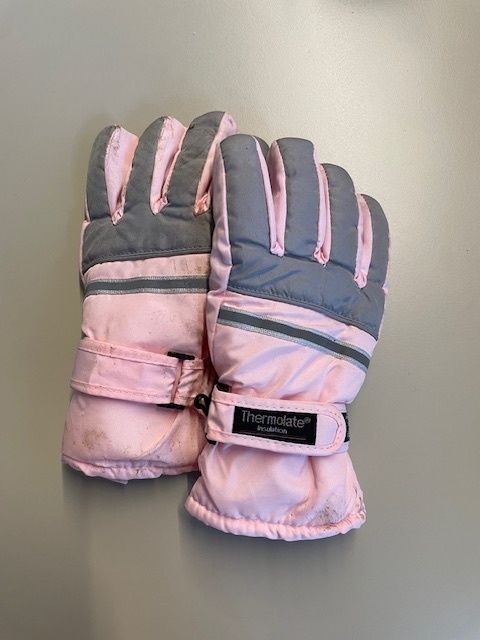 Ein Paar pinke und graue Winterhandschuhe mit einem schwarzen Etikett am Handgelenk. Sie sind von der Marke Thermolite.