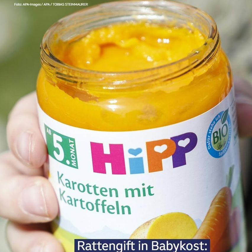 A hand holds a jar of HiPP baby food labeled 'Karotten mit Kartoffeln' (carrots with potatoes), with a BIO certification seal. The jar is filled with orange baby food.