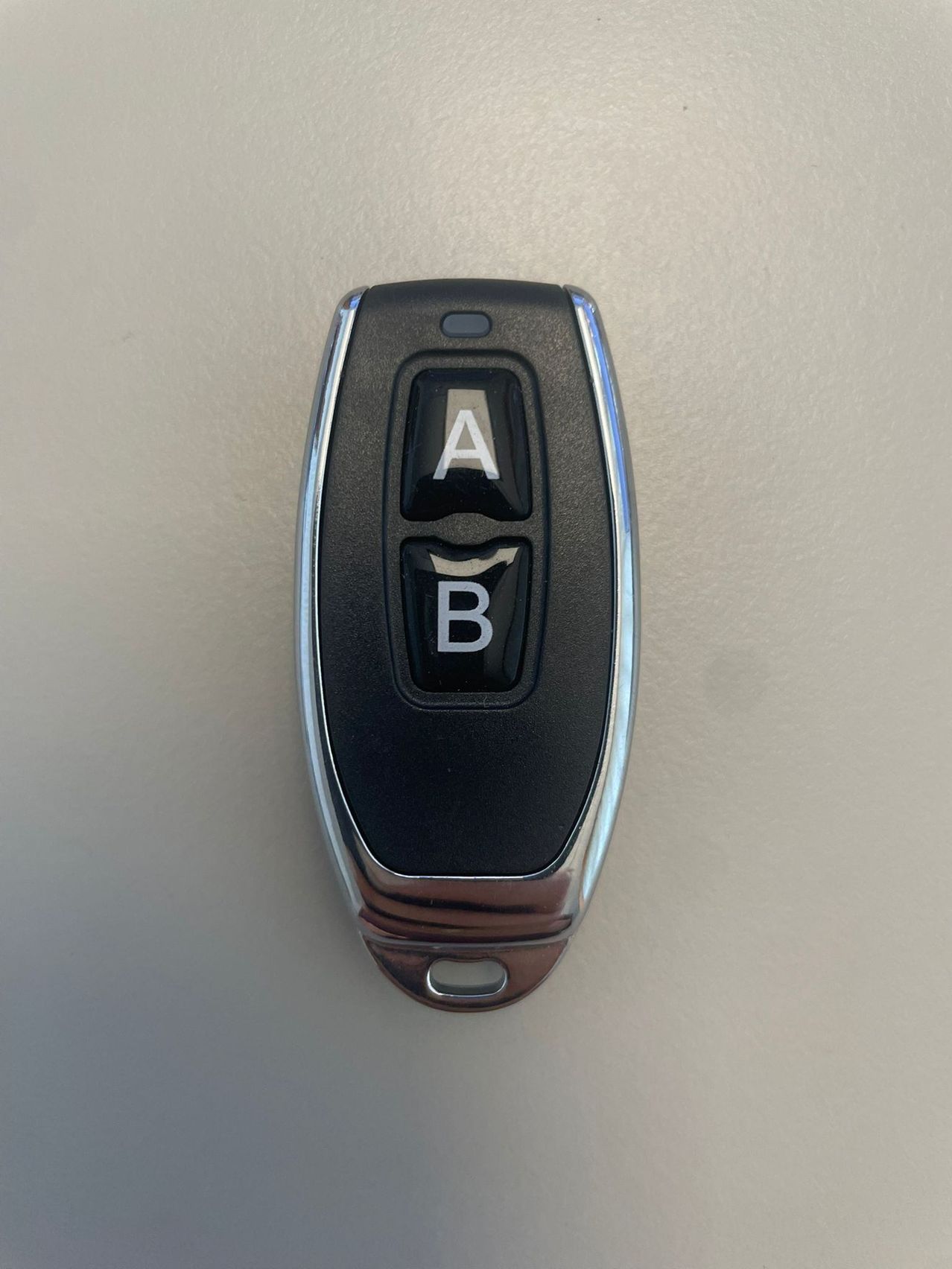 A close-up of a black and silver remote control with two buttons labeled A and B.