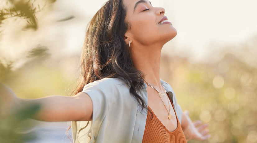 Eine Frau mit langen Haaren und einer Halskette schaut lächelnd nach oben in einer natürlichen Umgebung. Der Text 'Wenn dein Inneres endlich sicher sein darf' erscheint im Bild.