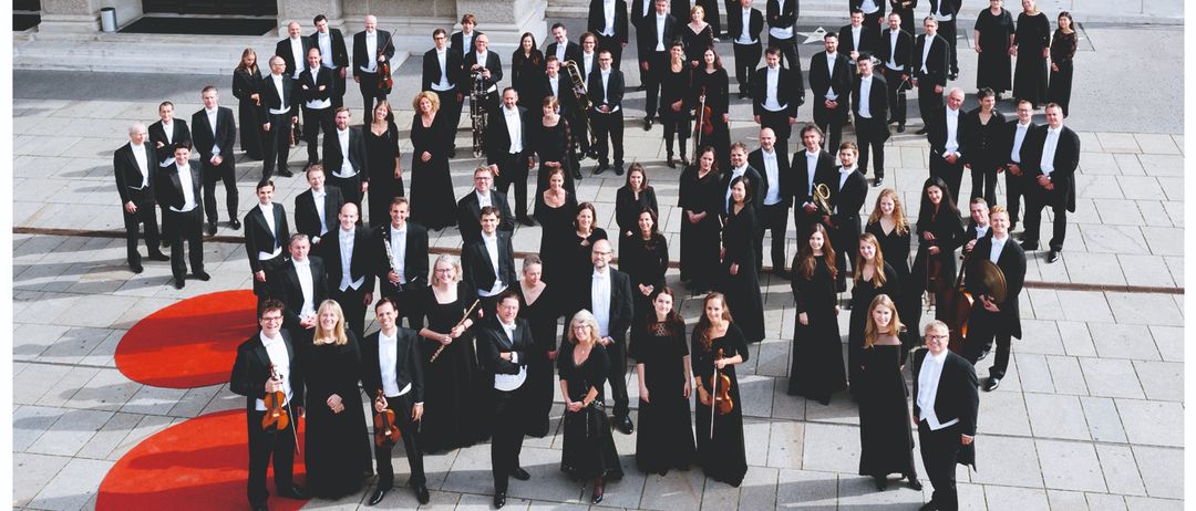 Neujahrskonzert von Niederosterreich, eine große Gruppe von Musikern im Kreis stehend in formeller Kleidung. Das Datum ist Donnerstag, 22. Jänner 2026, Beginn 19.30 Uhr. Die Veranstaltung findet im Festsaal Gymnasium in Laa a.d. Thaya statt.