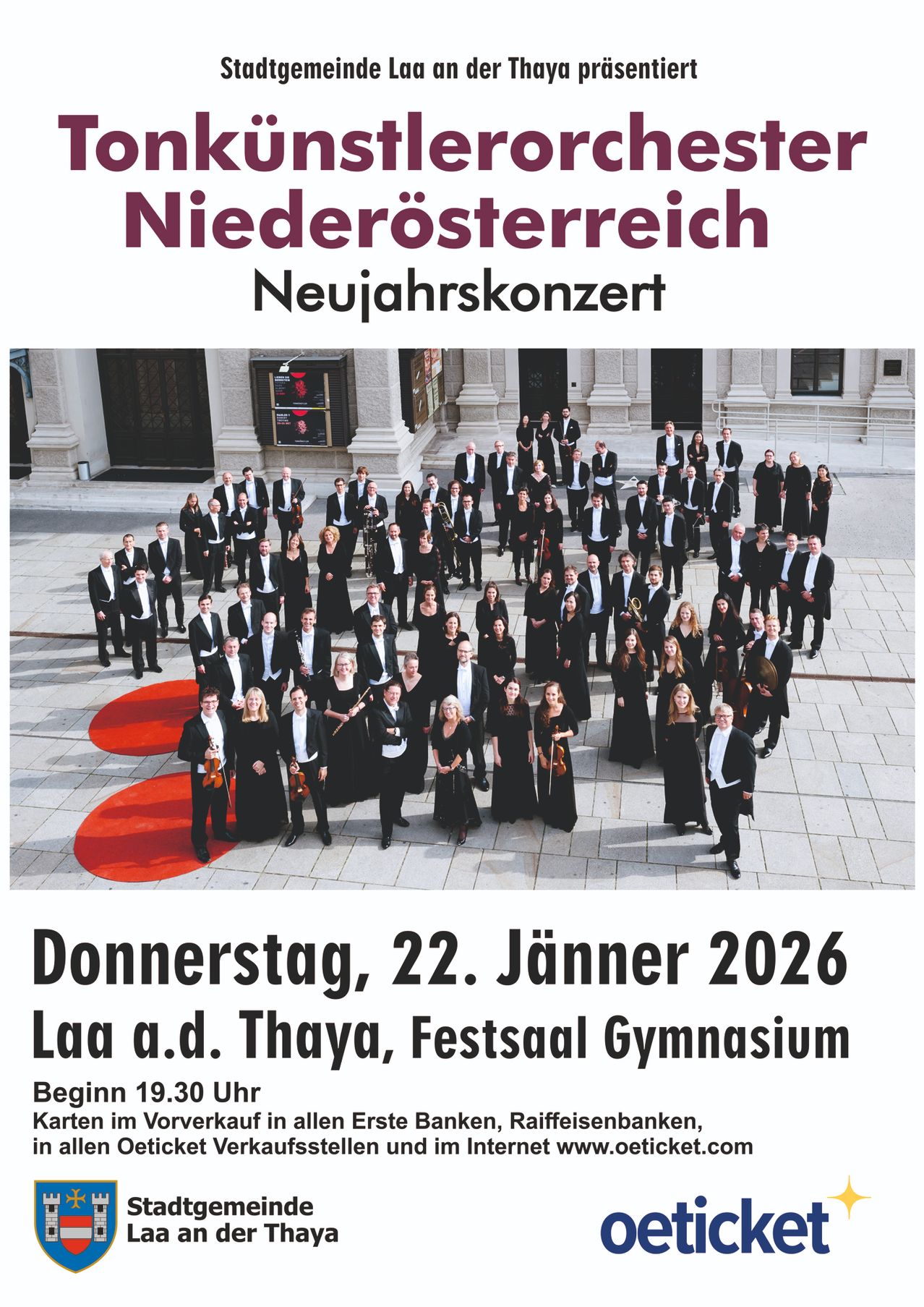 Ein Werbeplakat für ein Neujahrskonzert in Niederösterreich. Ein großes Orchester steht kreisförmig auf einer gepflasterten Fläche vor einem Gebäude. Der Text lautet 'Niederösterreich Neujahrskonzert' und das Datum 'Donnerstag, 22. Jänner 2026'.
