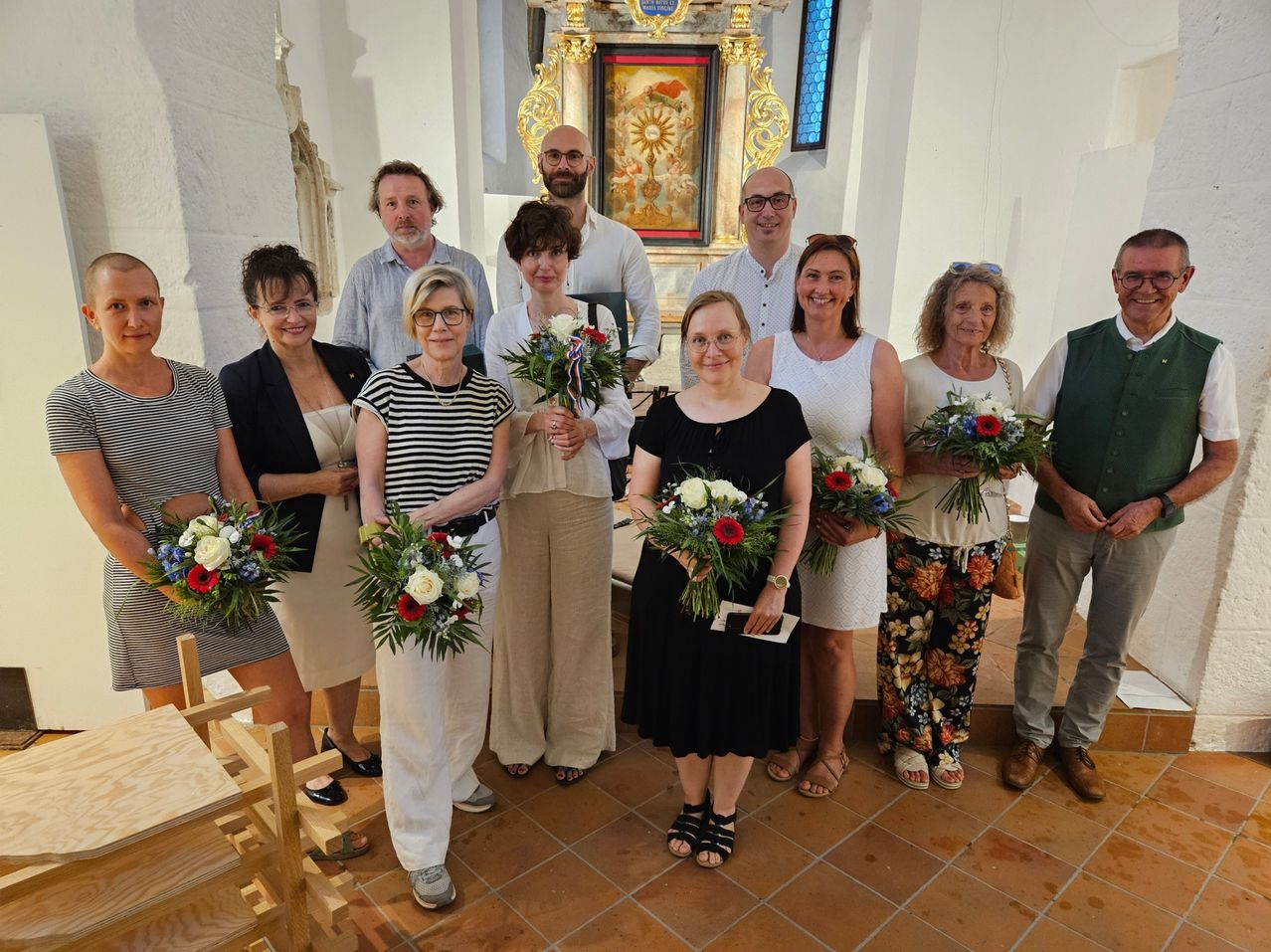 A group of people, possibly a family, are posing for a photo in a church with floral bouquets in their hands.