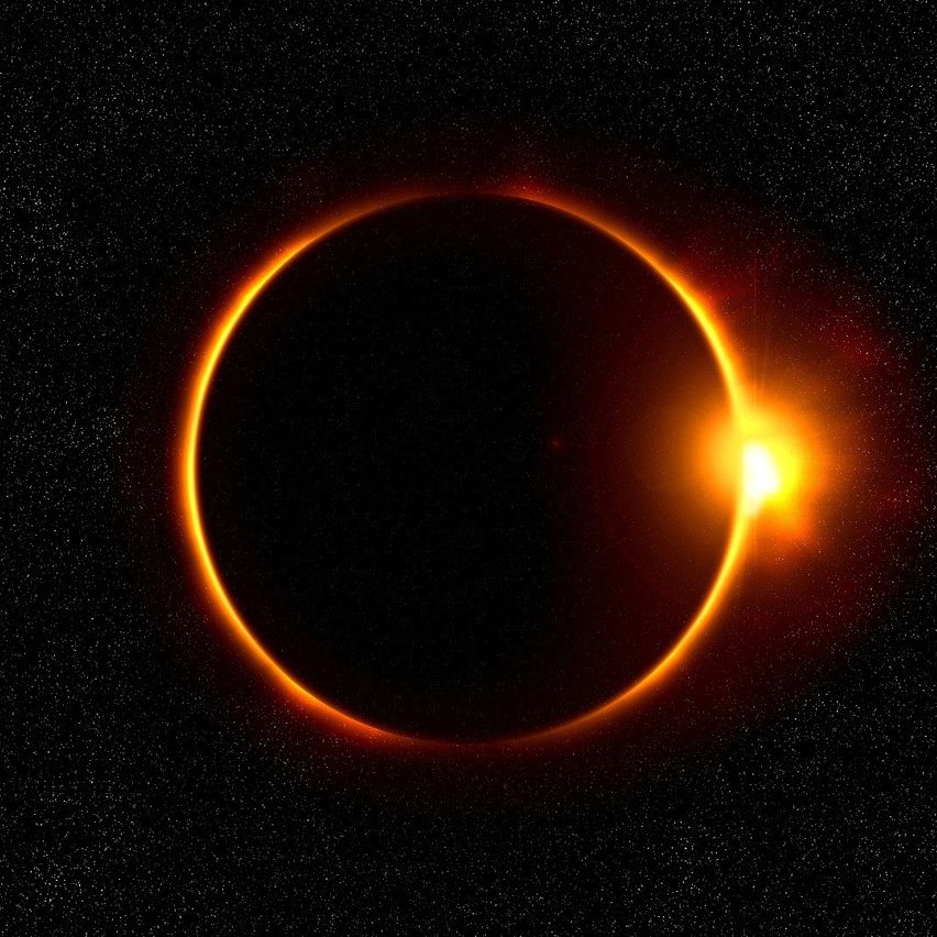 A solar eclipse with a dark sky, a bright sun, and a ring of fire around the moon.