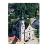 Ein Luftbild der historischen St. Martins-Kirche mit einem hohen Turm, umgeben von üppigem Grün und einer kleinen Stadt.