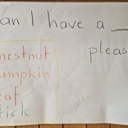 Eine handgeschriebene Notiz auf weißem Papier mit gelbem Rand. Die Notiz lautet 'Kann ich bitte eine Kastanie haben' mit 'Kastanie', 'Kürbis', 'Blatt' und 'Stock' hervorgehoben in Rot, Gelb und Grün.